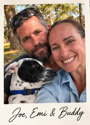 Polaroid-style photo of Joe and Emi smiling outdoors with their black-and-white dog, Buddy, captioned “Joe, Emi & Buddy”