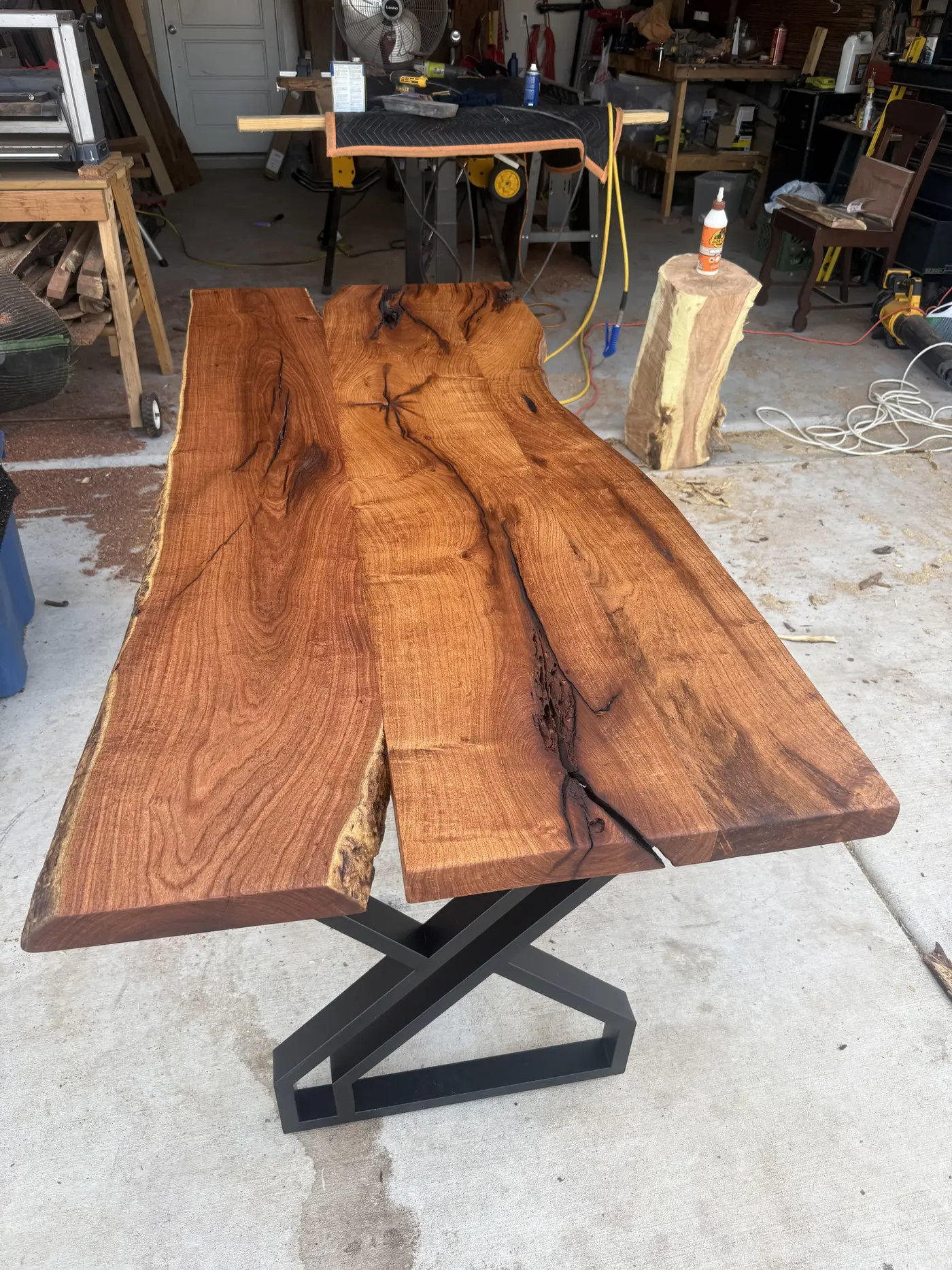 Live-edge slab desk top on a black steel base in the workshop