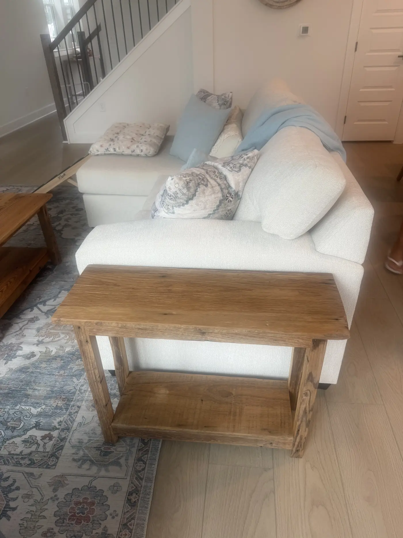 Reclaimed barn wood side table with a lower shelf beside a sofa in a client's home